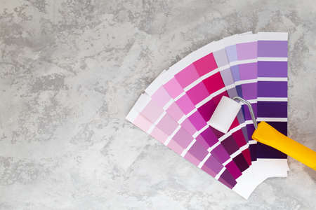 Colour Palette Catalog purple samples and roller for wall painting , paint selection cards on grey stone backgroundの写真素材