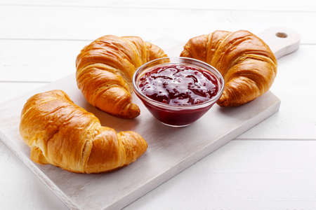 Traditional french croissant and strawberry jam on the white wooden table, tasty breakfastの写真素材