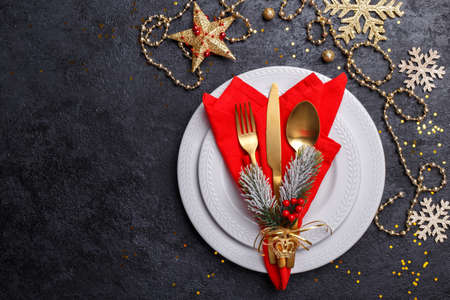 Christmas or new year table setting with golden cutlery on black stone table, card or menu template copy space flat layの写真素材