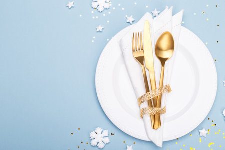 Christmas or new year table setting with golden cutlery on the blue background with copy spaceの写真素材