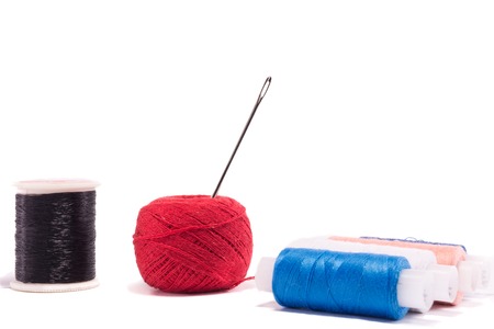Strands of red, blue, black and cherry blossom flowers with needle on white backgroundの写真素材