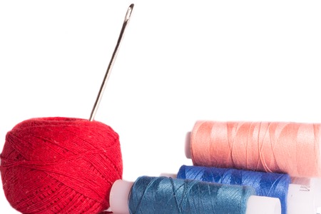 Strands of red, blue, black and cherry blossom flowers with needle on white backgroundの写真素材