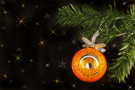 Big orange shiny mirror ball on new year tree on a black background with colorful stars.の写真素材