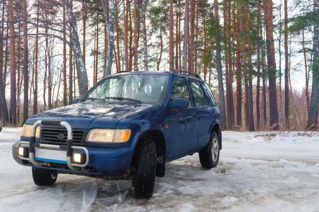 Blue off-road car standing in the woods in the winter