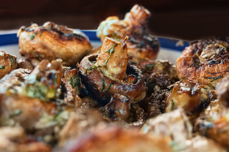 Whole mushrooms fried on a grill with spices of golden color on a plate.の写真素材