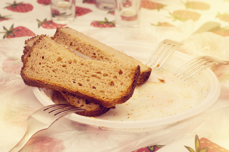 Three pieces of black bread on a plastic plate with and forks on a table