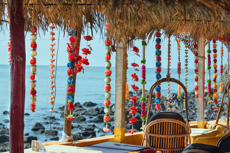 Thatched-roof cafe with Hawaiian and Asian flower wreaths. With sea views. India, Goaの写真素材