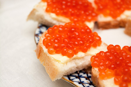 Sandwiches with red caviar and butter on a plate, lie on the tableの写真素材