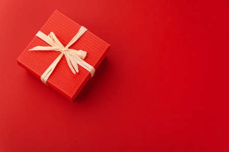 red gift box with a bow on a red background. present. holiday. love. packageの写真素材