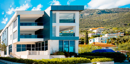 Modern house of two apartments with a beautiful garden directly on Lake Ceresio. Sunny day with blue sky. Minimalist and linear architecture. Panoramic view in background of green hills during summer.の写真素材