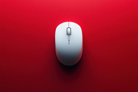 A white computer mouse is centered on a vibrant red background, highlighting its sleek curves and minimalist style ideal for modern workspaces.の素材