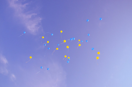 Festive multi-colored balloons in the blue sky with cloudsの写真素材