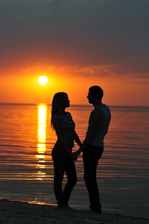woman and man on beach, silhouettes at sunsetの写真素材