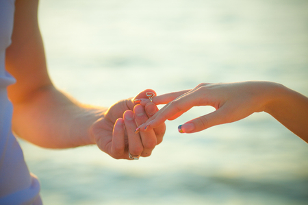 The young man makes a proposal of marriage. Wears a ring on her finger. Love, couple, date, wedding conceptsの写真素材