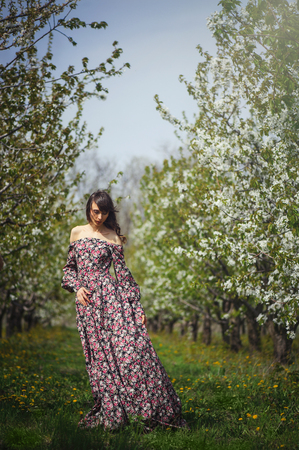 beautiful woman in long dress in blooming gardenの写真素材
