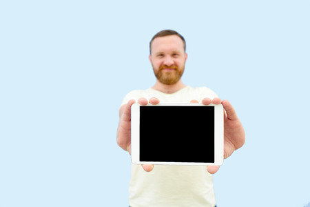 cheerful man with a red beard showing a tablet close-up, space for text.