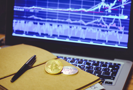 Bitcoin is a gold coin in the notebook of a business man against a computer background and an increasing graphics. The concept of virtual crypto currency.の写真素材