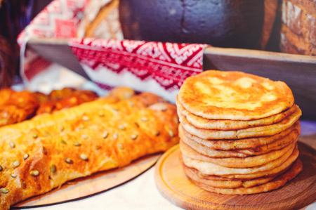 pile of air pancakes on a wooden dinette, a traditional food family. golden pancakes, pies in the background.の写真素材