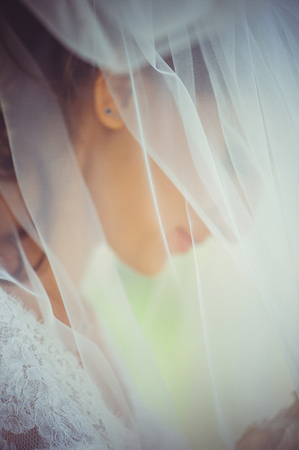  tender happy bride in a veil, a happy woman in a wedding dress, a white veil covers her face, gentle and warmの写真素材