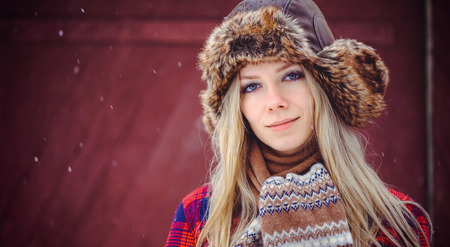tender woman in a winter hat and vareks on a red background, a bright advertising shot.の写真素材