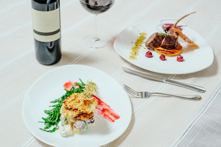 elegant appetizing veal with cherry sauce and turkey with Migdal. in white plates with greens, red wine and table setting.の写真素材