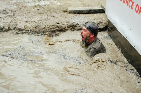 KYIV, UKRAINE - July 22, 2017: Men overcame the watery mud barrier during the Legion Legion Run race...