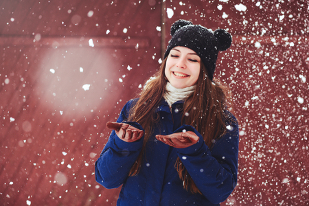 Winter portrait of a young woman. Beauty Joyous Model A girl laughs and is happy to have a dark red background. Beautiful young woman outdoors. Enjoy nature, in winter.の写真素材