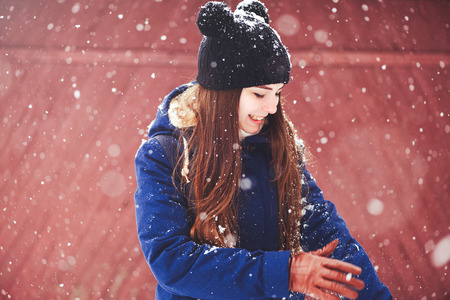 Winter portrait of a young woman. Beauty Joyous Model A girl laughs and is happy to have a dark red background. Beautiful young woman outdoors. Enjoy nature, in winter.の写真素材