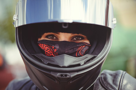 woman biker covers her face with a handkerchief and wears a helmet, safety on the road, close-up.の写真素材