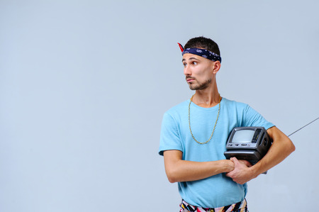 fashionable man in bright pants, with a small TV in his hands, the manifestation of emotions...