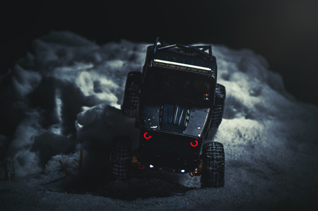 Radio-controlled car in the snow at night, lights shine. Christmas entertainment gift rc car.の写真素材