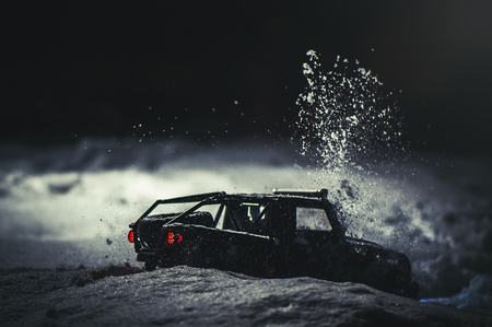 Radio-controlled car in the snow at night, lights shine. Christmas entertainment gift rc car.の写真素材