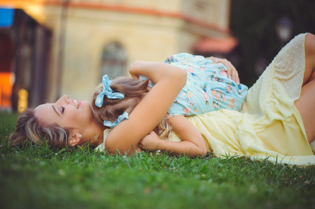 Beauty woman with child. Beautiful happy young woman is having fun lying on the grass and rejoicing hugging daughter - imageの写真素材