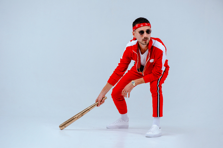 cheerful fashionable man wearing a red sports suit in his hand a gold baseball bat is more than a little surprised. proud and successful.の写真素材