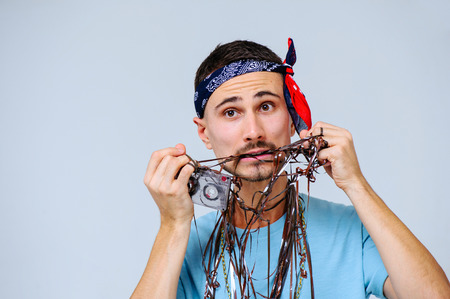 fashionable bright man with a film from audio cassettes in retro style the manifestation of emotions...