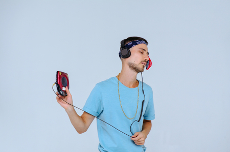 fashionable bright man with a film from audio cassettes in retro style the manifestation of emotions of joy, gestures with hands the place for text.の写真素材