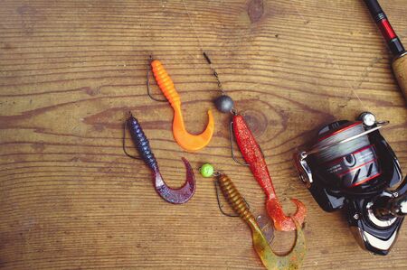 spinning fishing rods, fishing hooks, silicone baits on a woodenの写真素材