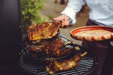 The chef checks the meat on the grill. Grilled golden ribs steaks, delicious food.の写真素材