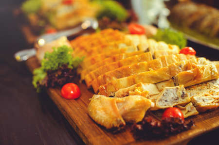beautiful chicken and mushroom pie with herbs, tomatoes and chicken legs on a wooden board in a restaurant. Selective focus, close-up.の写真素材