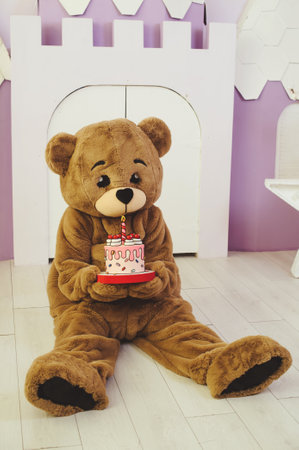 bear costume with holiday cake in hands for celebration, entertainment for children and adultsの写真素材