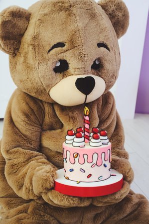 bear costume with holiday cake in hands for celebration, entertainment for children and adultsの写真素材