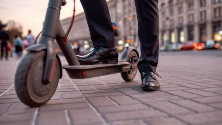 Cropped portrait of caucasian businessman in suit riding a scooter to work. Gas saving concept....