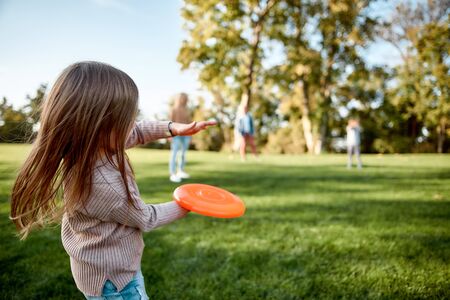 Making memories, breaking the distance. Little girl playing disk with her family in the park on a sunny dayの写真素材