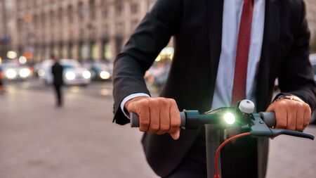 Take a ride. Businessman on daily commute riding scooter along the streetの写真素材