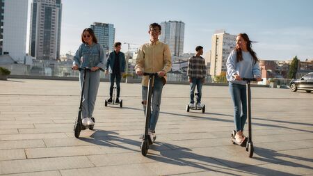 Full-length portrait of a group of millennials having fun while riding electric scooters and segways...