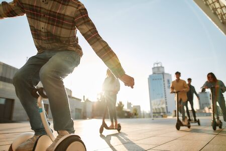 All Day Fun. A group of friends riding kick scooters  on a sunny dayの写真素材