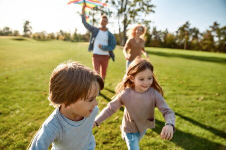 Children are living jewels. Happy family playing a kite. Outdoor family weekendの写真素材