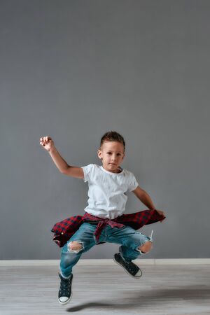 Active kid. Full length portrait of excited little boy in casual clothes jumping and looking at...