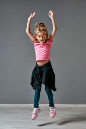 Full of energy. Portrait of a cute and excited little girl in casual clothes jumping in studio and looking at camera. Happy childrenの写真素材