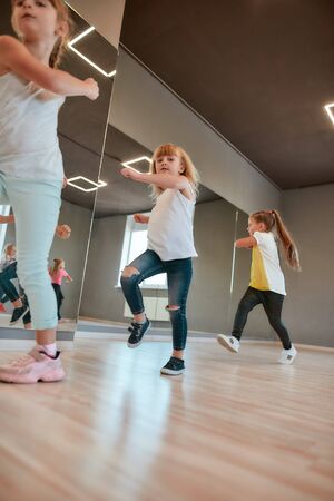Doing exercises. Little happy boys and girls warming up in the dance studioの写真素材